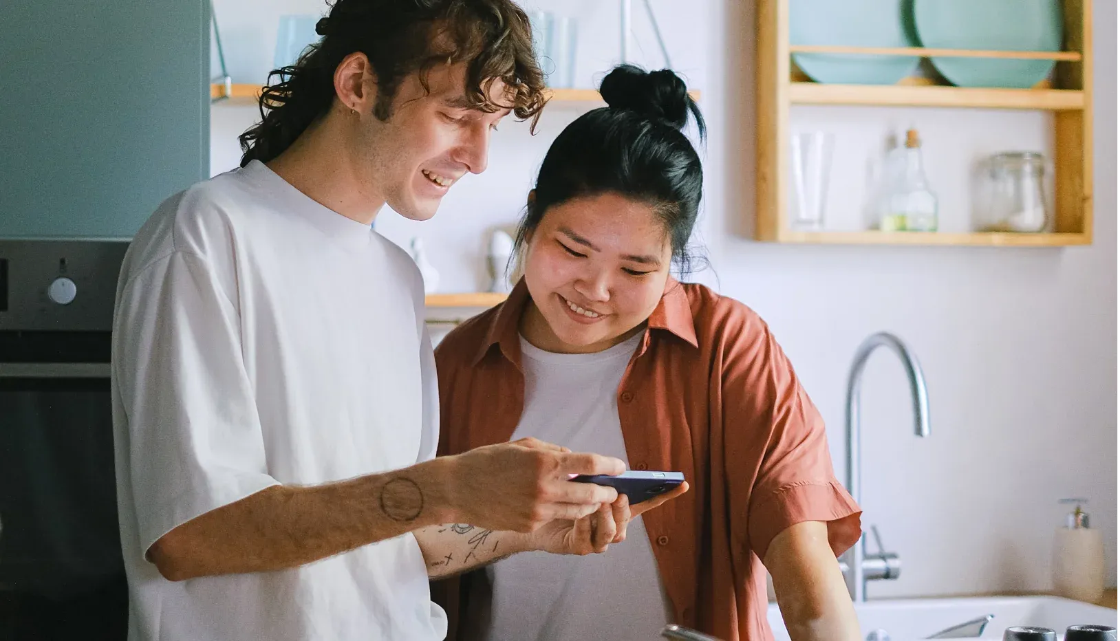 A man and a woman looking at the screen of a mobile phone together