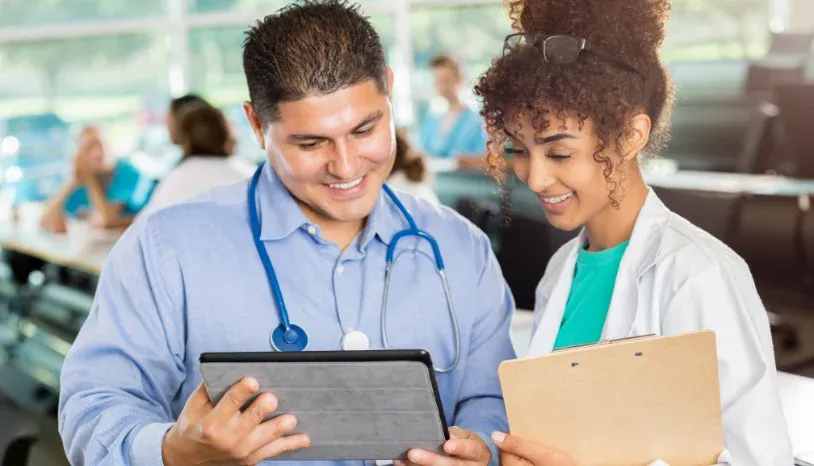 Smiling doctor and nurse looking at a tablet device