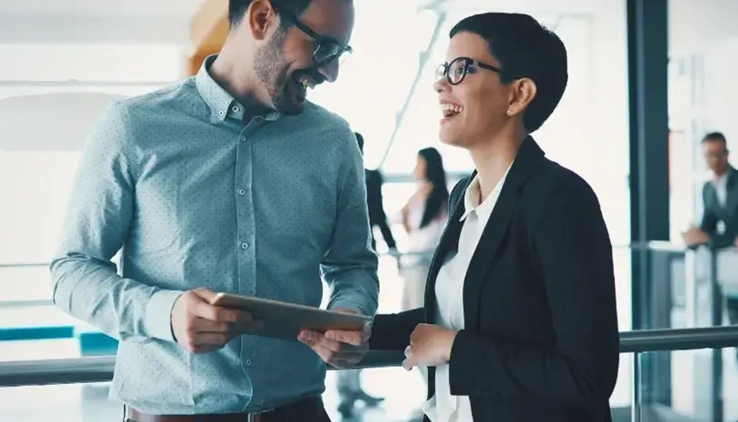 A man and woman in corporate wear smiling while looking at each other